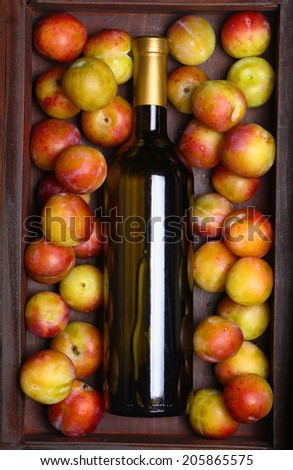 Bottle of white wine lying in a wooden case with plums