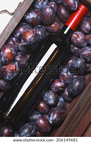 Bottle of red wine lying in a wooden case with plums