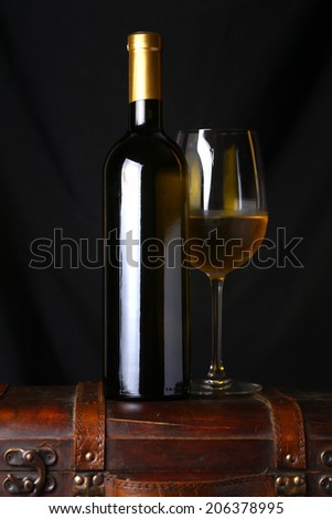 Bottle and glass of white wine standing on a wooden case