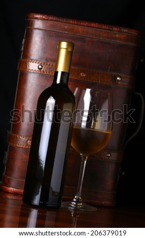 Bottle and glass of white wine with a wooden case in the background