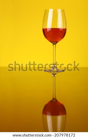 Glass of rose wine over a yellow background