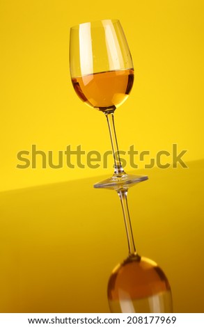 Glass of white wine over a yellow background