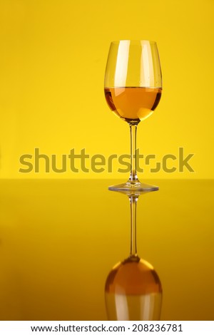 Glass of white wine over a yellow background