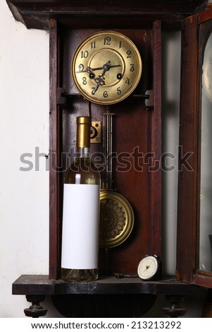 Bottle of white wine with blank label template standing inside an old clock
