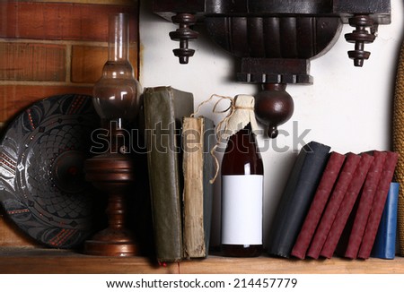 Bottle of craft beer with blank label template standing on a shelf with books under an old clock