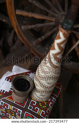 Old traditional bottle of Moldovan homemade wine with clay cup and old wheels in the background