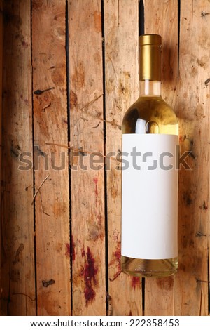 Bottle of white wine with a blank label in a used wooden crate with grape juice marks