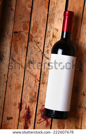 Bottle of red wine with a blank label in a used wooden crate with grape juice marks