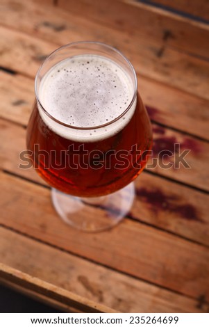 Glass of amber beer standing in an old dirty wooden crate