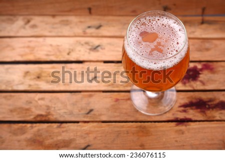 Glass of light beer standing in a dirty old wooden crate