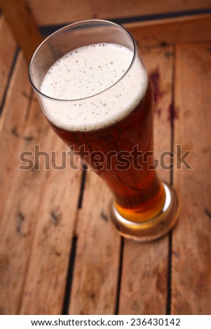 Tall glass of amber beer standing in an old dirty wooden crate