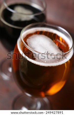 Full glass of dark and ligth beer standing in a wooden case