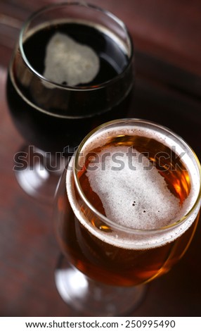 Full glass of dark and ligth beer standing in a wooden case