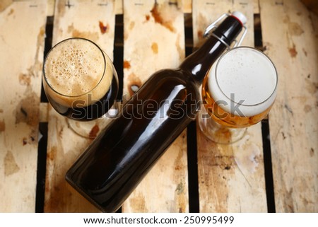 Bottle and full glasses of beer looking as a percent sign in a dirty wooden crate