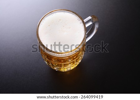 Classic glass mug full of light lager beer shot topdown over a dark background