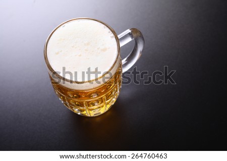 Classic glass mug full of light lager beer shot topdown over a dark background