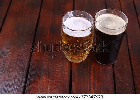 Classic mug and pint glasses full of light and dark beer standing on a wooden table