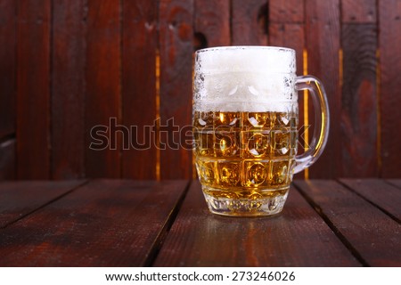 A classic mug full of light beer standing on a wooden table