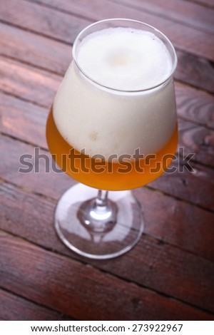 Glass full of unfiltered wheat beer standing on a wooden table