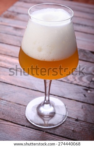 Glass full of unfiltered wheat beer standing on a wooden table