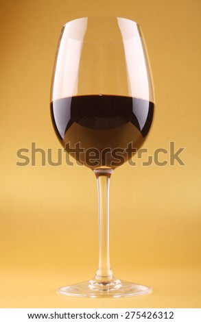 Tall glass with red wine over a bright yellow background