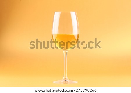 Tall glass with white wine over a bright yellow background