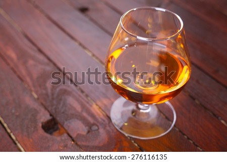 Snifter glass full of brandy standing on a wooden table