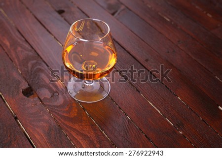 Snifter glass full of brandy standing on a wooden table