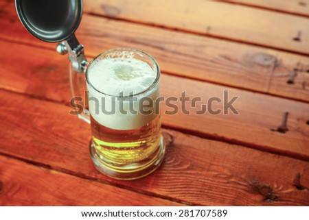 Light beer pouring into a mug standing on a wooden table