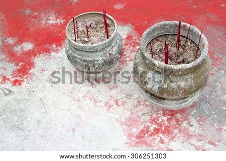 Rustic incense burner with incense sticks on a grunge background. These incense sticks are used during Buddhist rituals for praying and meditation