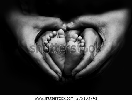 New born baby\'s feet on parents hand - Black and White image