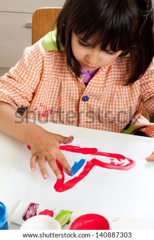 Concentrated little girl painting with fingers
