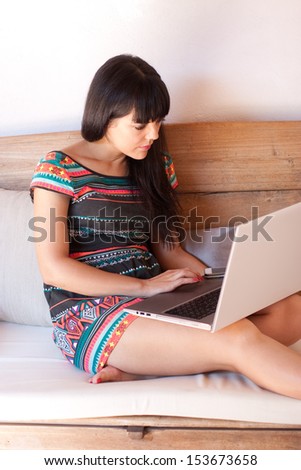 Young woman working on vacation with a laptop while sitting in a rustic sofa