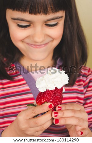 Happy cute little girl about to eat a strawberry with cream. Focus on hands with red polished nails and strawberry. Old film effect added.