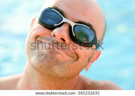Man with goggles in the pool with a funny expression of happiness. Soft focus.