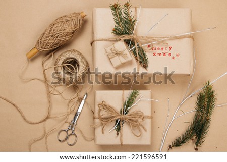 Wrapping eco Christmas packages with brown paper, string and natural fir branches