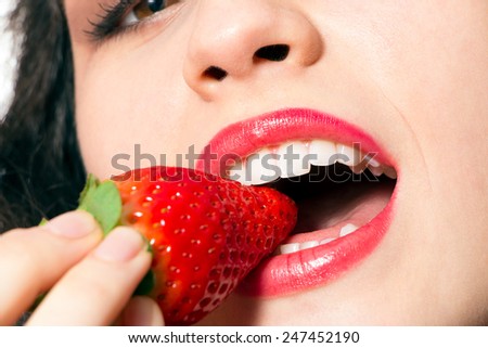 Close up of sexy woman mouth with red lips biting strawberry