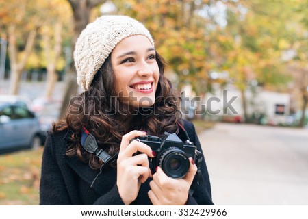 Happy young beautiful woman with an analog camera capturing autumn in the city