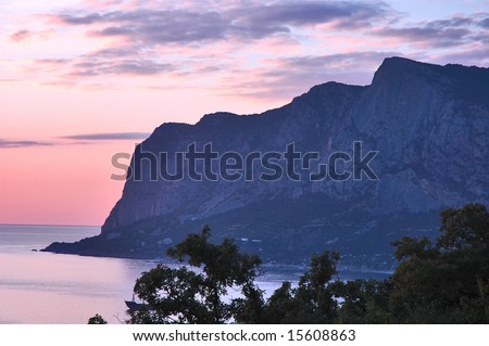 Morning in mountains. Pink sky and dark mountain background.