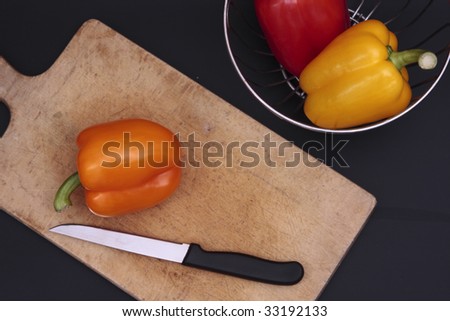 three bell peppers with chrome basket and chopping board