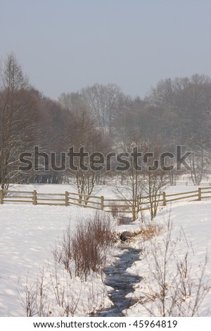 winter farmland with little creek in picturesque valley