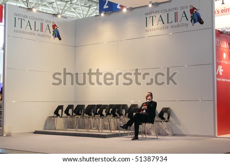 HANNOVER, GERMANY - APRIL 19: businessman with cellphone on the stand of italy, this years partner country, at the hannover industrial fair , Hannover Messe April 19, 2010 in Hannover, germany