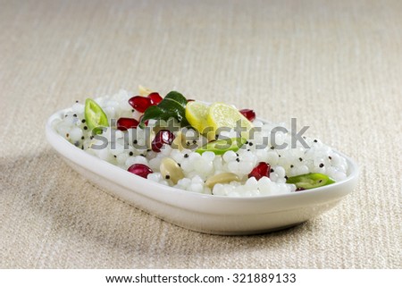 Sabudana (Sago) Khichadi topped with pomegranate seeds, curry leaves, chopped green chillies and lemon slices.
