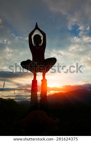 Acroyoga girl of male in romantic atmosphere in the nature in the mountains at sunset