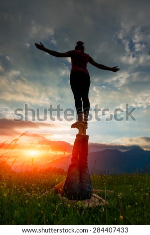 Acroyoga girl of male in romantic atmosphere in the nature in the mountains at sunset