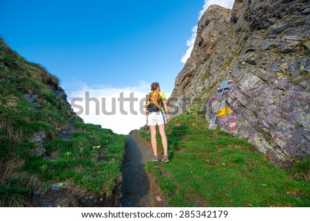 Girl looks indications mountain trail in a mountain pass