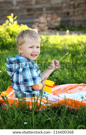 beautiful little boy draws in summer park