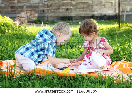 beautiful little boy and girl draw in summer park