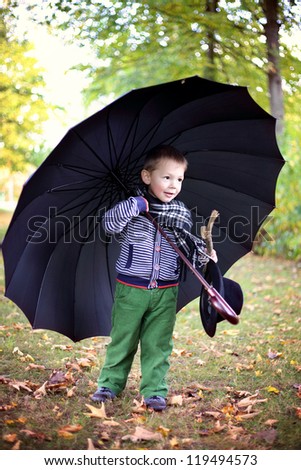 little gentleman with big black umbrella in autumn park