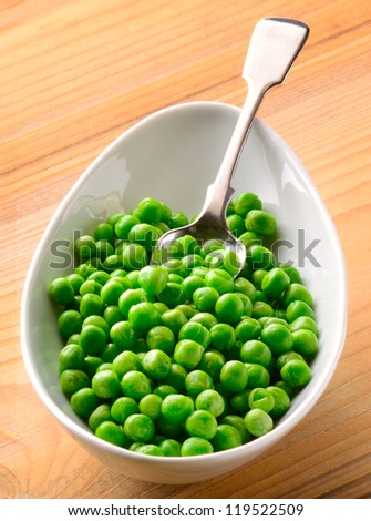 Fresh green peas in serving dish with spoon